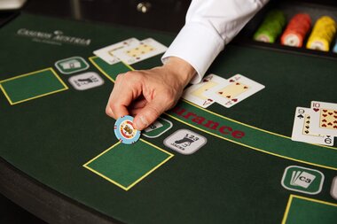 Close-up of a casino blackjack table with a hand placing a betting chip. | © Casinos Austria