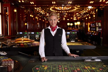 A person standing at a roulette table in an elegant casino with gold decorations and lighting. | © Casinos Austria