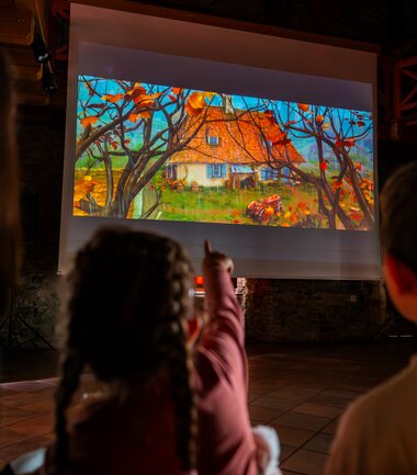Children watching a movie on a large screen in a cozy venue, during a children's cinema event. | © Zell am See-Kaprun Tourismus