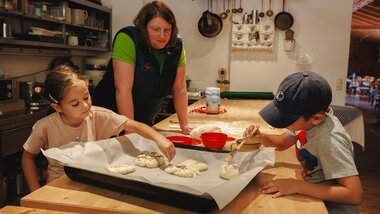 Children baking with an adult in the kitchen, dough on a baking tray. | © Zell am See-Kaprun Tourismus