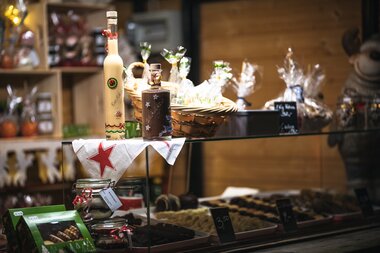 Festive market stands with drinks, baked goods, and decorations, decorated for an Advent event. | © Johannes Radlwimmer