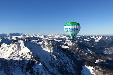 Hot air balloon flying over snow-covered mountains in Zell am See-Kaprun on a clear day. | © Zell am See-Kaprun Tourismus