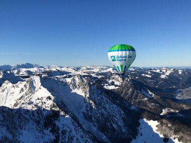 Hot air balloon flying over snow-covered mountains in Zell am See-Kaprun on a clear day. | © Zell am See-Kaprun Tourismus