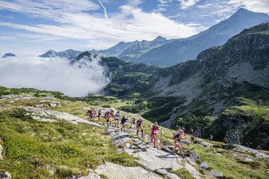 Groups of hikers in a mountainous landscape with clouds and high peaks. | © wisthaler.com