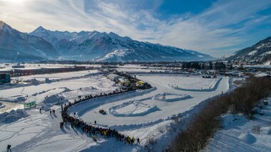 View of the snowy race track at the GP Ice Race against a mountain landscape. | © Nikolaus Faistauer Photography