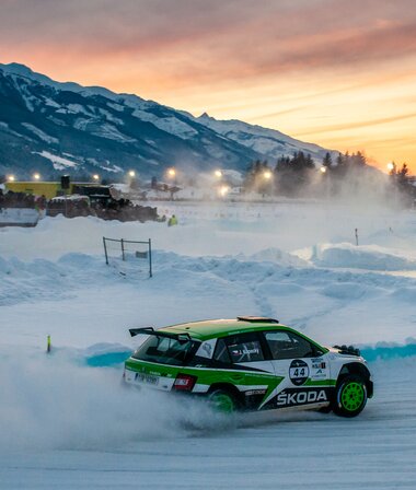 A rally car on a snowy track at sunrise, racing on ice with mountains in the background. | © Pavel Jaremenko
