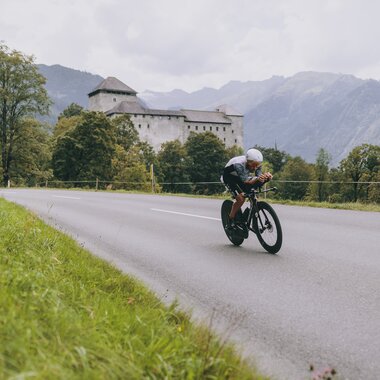 A cyclist during IRONMAN 70.3 in Zell am See-Kaprun on a winding road amidst scenic mountain landscape. | © Zell am See-Kaprun Tourismus
