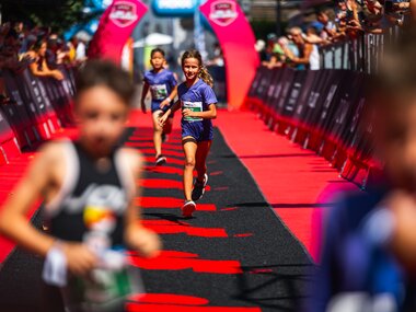 Children running at the finish area of an Ironman event in Zell am See-Kaprun while spectators watch the race. | © Zell am See-Kaprun Tourismus