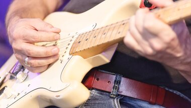 Close-up of a guitarist playing an electric guitar. | © artisual