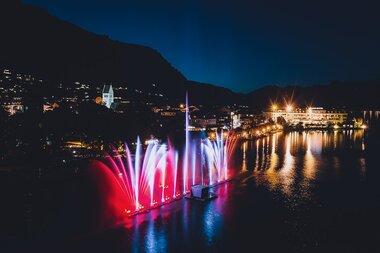 Evening water fountains with colorful lights on Lake Zell near Zell am See, Alps in the background | © EXPA, Jürgen Feichter