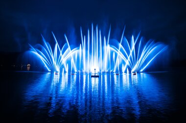 Illuminated water fountains during a night water and light show on a lake. | © Zell am See-Kaprun Tourismus
