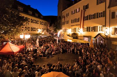 View of a summer night festival with a large crowd in a city during the night, illuminated by streetlights. | © Zell am See-Kaprun Tourismus