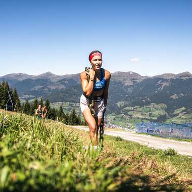Participant in the Spartan Race in Zell am See-Kaprun, surrounded by mountains and green landscape, running on a mountain meadow during the race. | © Zell am See-Kaprun Tourismus