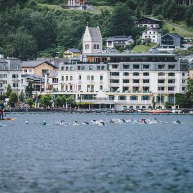 View of Lake Zell in Zell am See with several sailors and a hotel along the shore, scenic mountain background. | © EXPA, Jürgen Feichter
