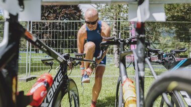 Person preparing for a bike ride outdoors, surrounded by bicycles in a secured area. | © EXPA, Jürgen Feichter