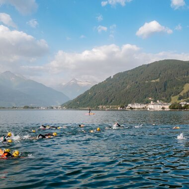 Swimmers competing in a race on a lake surrounded by mountains with a lively atmosphere. | © Zell am See-Kaprun Tourismus