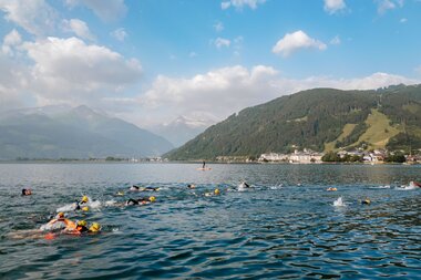 Swimmers competing in a race on a lake surrounded by mountains with a lively atmosphere. | © Zell am See-Kaprun Tourismus