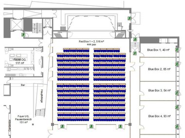 Conference center hall with tiered seating arranged in a parliamentary layout, surrounded by several blue and green boxes.