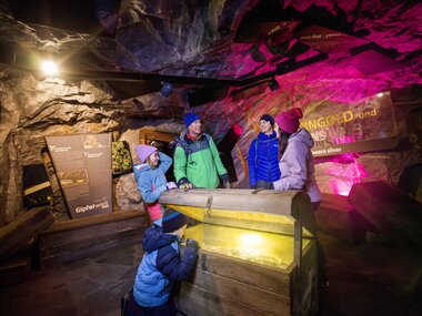 A group exploring a cave with rock walls and colorful lighting inside. | © Kitzsteinhorn
