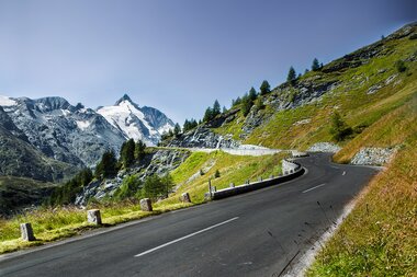 Winding road on the Grossglockner High Alpine Road with mountains in the background and snow on the peaks. | © Andreas Kolarik
