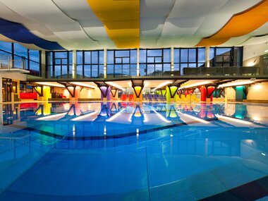 Interior of a modern indoor swimming pool with colorful, vaulted ceilings and a large pool. | © Johannes Felsch