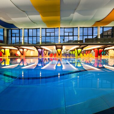 Interior of a modern indoor swimming pool with colorful, vaulted ceilings and a large pool. | © Johannes Felsch