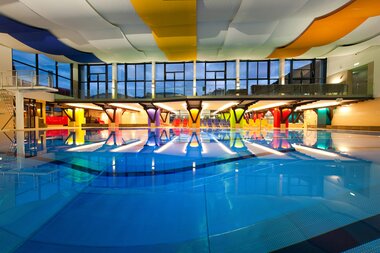 Interior of a modern indoor swimming pool with colorful, vaulted ceilings and a large pool. | © Johannes Felsch