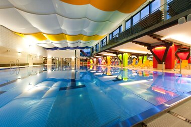 Interior of a modern indoor swimming pool with colorful ceiling and water slide. | © Johannes Felsch