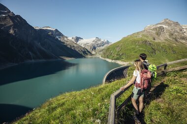 Hiker with a backpack on a trail overlooking a high mountain lake in the Alps. | © Zell am See-Kaprun Tourismus