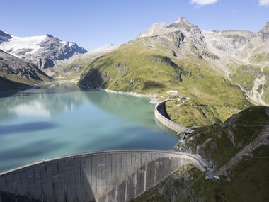 View of the Mooserboden reservoir in the Austrian Alps, surrounded by mountains and glaciers, with a spillway and Mooser dam. | © VERBUND, Johannes Wiedl