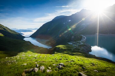 High-altitude reservoirs in a mountainous landscape with lakes and green slopes, illuminated by sunlight. | © VERBUND 