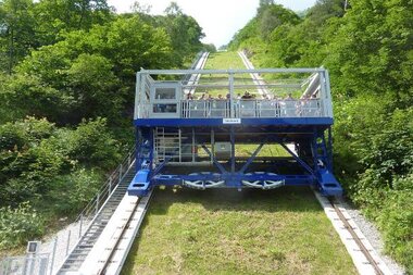 A funicular at high mountain reservoir with visible cable system, surrounded by green nature. | © VERBUND