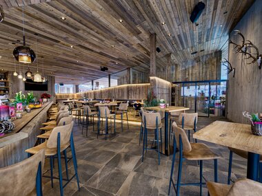 Interior of a modern restaurant with wood-paneled walls, seating, and decorative elements. | © Schmittenhöhe
