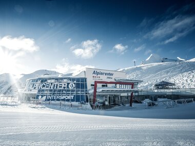 Alpincenter in snowy mountain landscape with ski hut and ski slope under sunny sky. | © Kitzsteinhorn