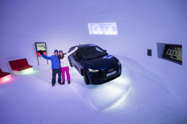 Two people posing next to a black Audi car in an ice-camp setting with illuminated Audi signs. | © Kitzsteinhorn