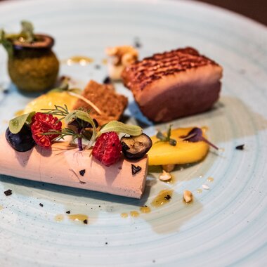 Elegant dish with poultry, side dishes, and garnishes on a blue ceramic plate | © Tauern SPA Zell am See-Kaprun