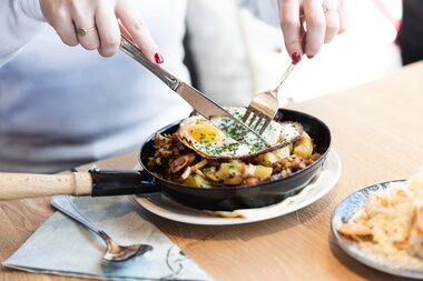 Traditional Austrian farmer's dish with fried egg, potatoes, and bacon served in a pan. | © Zell am See-Kaprun Tourismus