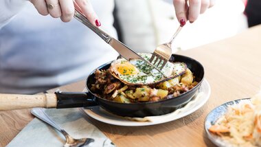 Traditional Austrian farmer's dish with fried egg, potatoes, and bacon served in a pan. | © Zell am See-Kaprun Tourismus
