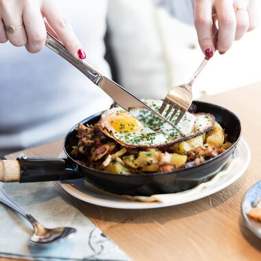 Traditional Austrian farmer's dish with fried egg, potatoes, and bacon served in a pan. | © Zell am See-Kaprun Tourismus