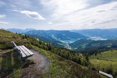 Viewpoint overlooking mountains, valley, and lake, with a bench for resting | © Zell am See-Kaprun Tourismus