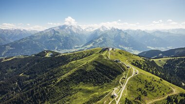 Scenic view of green hills and mountain ranges on a clear day, viewed from above the Schmittenhöhe in Austria. | © Zell am See-Kaprun Tourismus