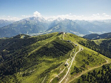 Scenic view of green hills and mountain ranges on a clear day, viewed from above the Schmittenhöhe in Austria. | © Zell am See-Kaprun Tourismus