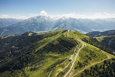 Scenic view of green hills and mountain ranges on a clear day, viewed from above the Schmittenhöhe in Austria. | © Zell am See-Kaprun Tourismus