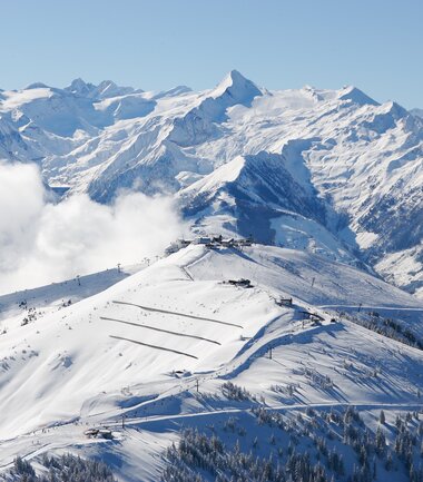 Aerial view of a snowy mountain landscape with high peaks and a clear blue sky. | © Zell am See-Kaprun Tourismus