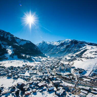 Winter landscape with snow-covered mountains and a village in a valley under bright sunshine. | © Zell am See-Kaprun Tourismus
