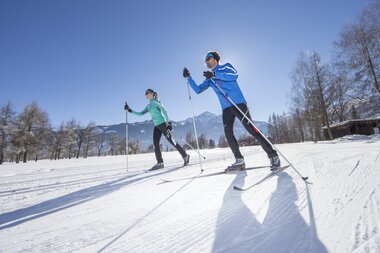 Two cross-country skiers on snowy terrain in Zell am See-Kaprun on a sunny day. | © Nikolaus Faistauer Photography