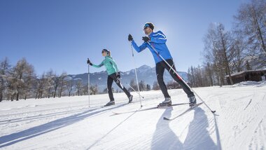 Two cross-country skiers on snowy terrain in Zell am See-Kaprun on a sunny day. | © Nikolaus Faistauer Photography