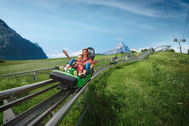 Enjoying a summer toboggan ride with mountain views and a peak in the background. | © Kitzsteinhorn