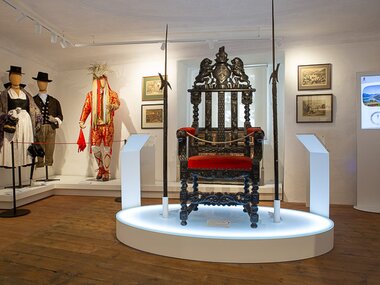 Exhibition with historical clothing and a ornate, antique throne in a museum. | © Peter Brand