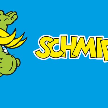Cartoon dragon named Schmidolin with a lively movement on a blue background, next to the text "Schmidolin". | © Schmittenhöhe
